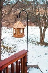 Lawn Hook Deck Mount 41" installed on a wooden deck railing, holding a wooden bird feeder in a snowy backyard garden setting.