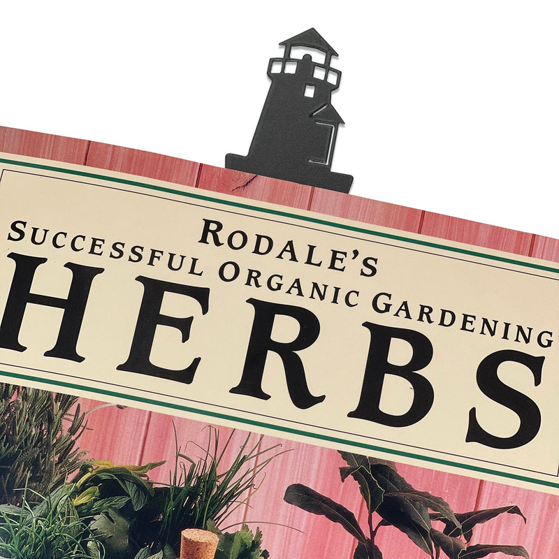 Textured Lighthouse Bookmark clipped to a book, showcasing its decorative lighthouse top and sturdy metal construction for daily use.