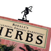 Garden Fairy Bookmark -Flat Black peeks over a book cover, showcasing its elegant fairy design. Perfect for marking pages with style and charm.