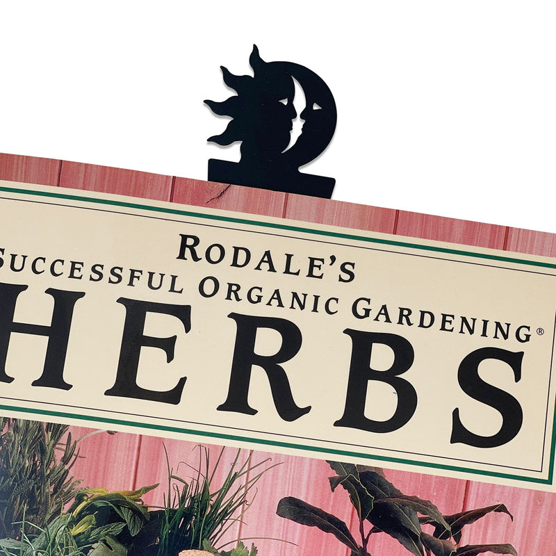 Sun & Moon Bookmark -Flat Black clipped onto a book, showcasing its celestial design and functionality for home or office use.