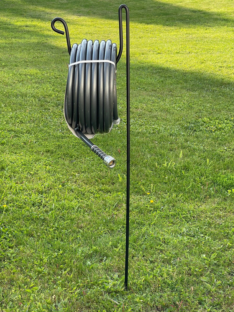 Hose Holder Round Large holding coiled black hose in grassy yard, perfect for keeping hoses off the ground and tangle-free outdoors.