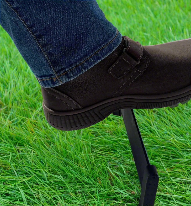 Boot Scraper in use outdoors, removing dirt from a black boot on green grass; ideal for keeping footwear clean before entering the home.