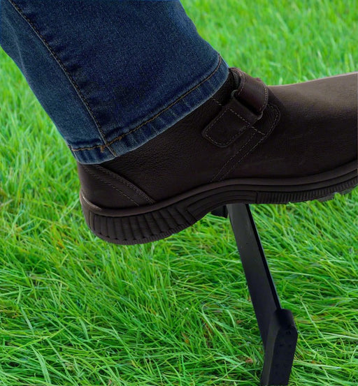 Boot Scraper in use outdoors, removing dirt from a black boot on green grass; ideal for keeping footwear clean before entering the home.