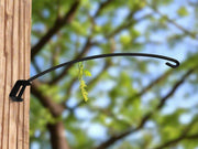 Swivel Plant Hanger 18 In. mounted on wooden post outdoors, supporting a hanging plant in a garden setting.