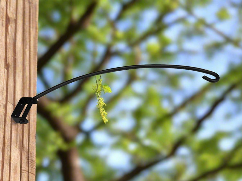 Swivel Plant Hanger 18 In. mounted on wooden post outdoors, supporting a hanging plant in a garden setting.