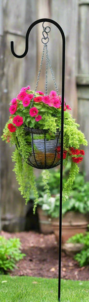 56"H Lawn Hook - 3/8" Solid Square Iron holding a hanging flower basket in a landscaped garden, ideal for outdoor plant display.