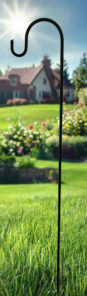 50-inch solid iron lawn hook installed in grassy yard with house and flower garden in background, ideal for outdoor decor.