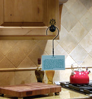 Recipe card hanger hook mounted on a wooden kitchen cabinet, displaying a recipe card above the counter for hands-free cooking.