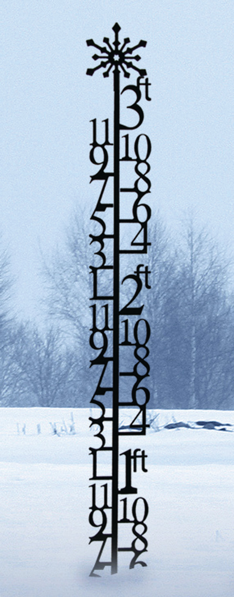 Tall 3 Foot Snowflake Snow Gauge standing in snow-covered yard, featuring large numeric markers for precise snowfall measurement.