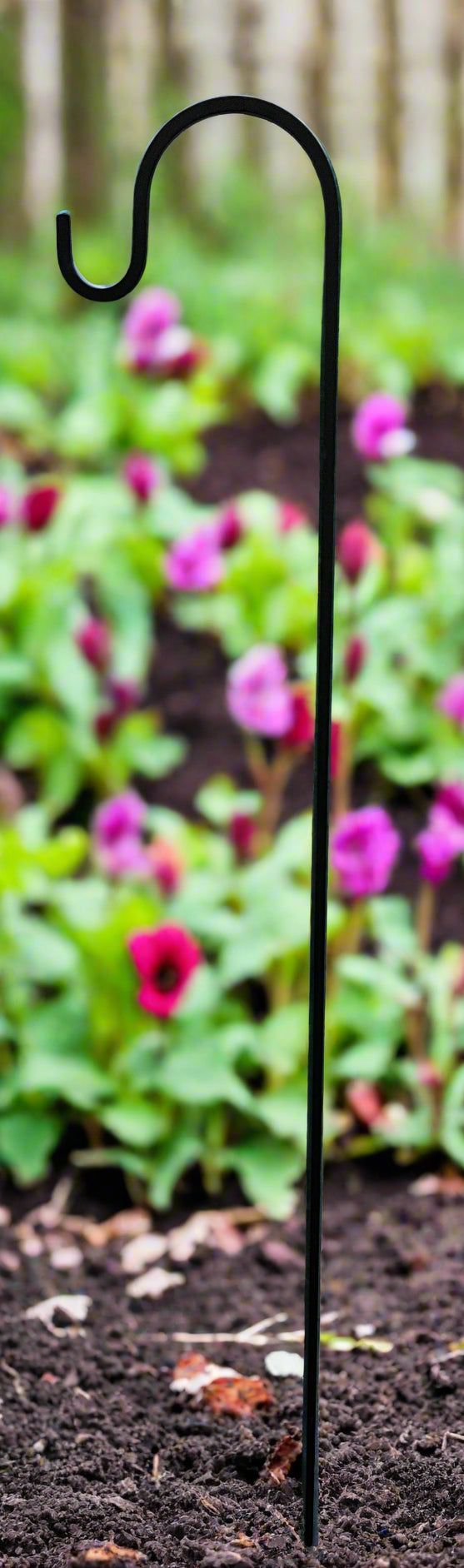50-inch solid iron lawn hook staked in soil among blooming flowers, perfect for hanging planters or garden ornaments.